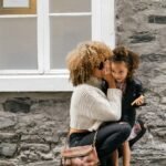 woman wearing white sweater carrying a daughter